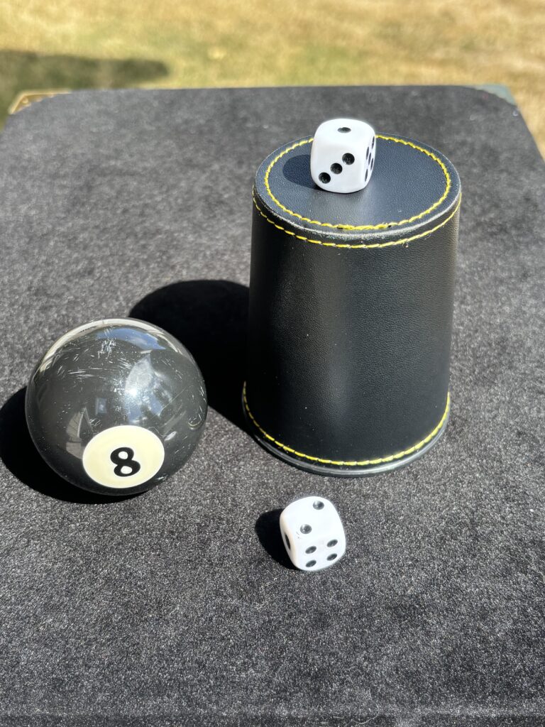 an eight ball, dice and dice cup for the chop cup magic trick