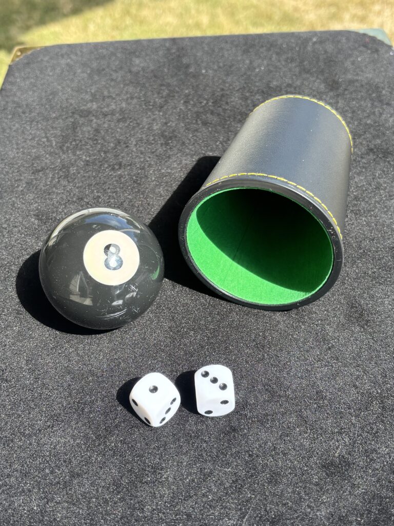 A dice cup, two dice and an eight ball for the chop cup magic trick