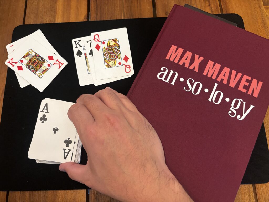 A hand with cards and a Magic book by Max Maven